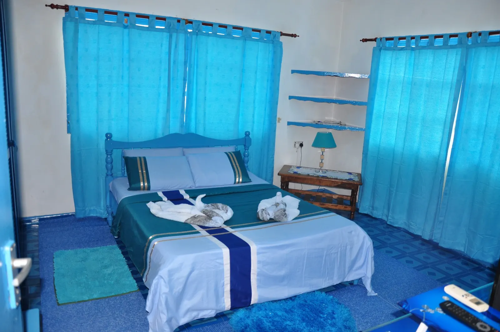 Standardzimmer im Chateau Bleu mit Doppelbett, blauer Tagesdecke und Vorhängen